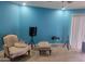 Bright living room features cozy armchair, ottoman, turquoise walls and tile floor at 4549 W Seldon Ln, Glendale, AZ 85302