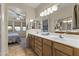 Bathroom vanity with dual sinks, wood cabinets, and adjacent bedroom view at 5450 E Mclellan Rd # 145, Mesa, AZ 85205
