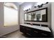Bright bathroom featuring a large window, dual sinks, wood cabinets, and a view to the walk-in shower at 656 W Johnson Dr, Gilbert, AZ 85233