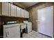 Functional laundry room featuring a washer, dryer, utility sink, and ample storage cabinets for organization at 656 W Johnson Dr, Gilbert, AZ 85233