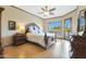 Bright main bedroom featuring a ceiling fan, wood floors, and a backyard pool view at 7517 E Mariposa Grande Dr, Scottsdale, AZ 85255