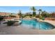 Backyard oasis with a lagoon-style pool, rock waterfall, and lush landscaping at 7517 E Mariposa Grande Dr, Scottsdale, AZ 85255