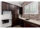 Laundry room with granite countertops, ample cabinet space, and brick accent wall at 823 W Palo Verde Dr, Phoenix, AZ 85013