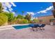 Backyard pool area with lounge chairs, lush landscaping, a built-in BBQ, and a clear blue sky at 823 W Palo Verde Dr, Phoenix, AZ 85013