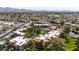 Drone view showing the apartment complex, community pool, palm trees, grassy lawns, and stunning views of the distant mountains at 8256 E Arabian Trl # 239, Scottsdale, AZ 85258