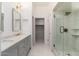 Bright bathroom featuring double sinks, a marble countertop, and a glass-enclosed shower with a walk-in closet at 902 W Glendale Ave # 215, Phoenix, AZ 85021