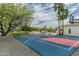 Outdoor basketball court with blue and red paint, surrounded by gravel, trees, and a glimpse of the pool area at 9053 N 123Rd St, Scottsdale, AZ 85259
