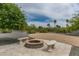 An inviting outdoor fire pit area with built-in seating, surrounded by greenery and desert landscaping at 9053 N 123Rd St, Scottsdale, AZ 85259