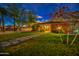 Beautiful house with manicured lawn, stone walkway and mature trees, offering great curb appeal at twilight at 1402 E Granada Rd, Phoenix, AZ 85006