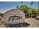 Charming community sign with desert landscape art and address against a backdrop of lush trees at 1440 N Idaho Rd # 2053, Apache Junction, AZ 85119