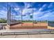 Baseball field enclosed in fencing, with team on the field, bleachers, and views of neighborhood at 14413 W Dahlia Dr, Surprise, AZ 85379