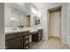 Bright bathroom featuring a double vanity with dark cabinets, a glass-enclosed shower, and wood-look flooring at 14413 W Dahlia Dr, Surprise, AZ 85379