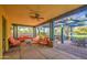 Inviting covered patio with comfortable seating, ceiling fan, and outdoor dining area overlooking the lush green landscape at 14413 W Dahlia Dr, Surprise, AZ 85379