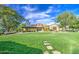 Charming exterior view with lush green lawn, mature trees, and inviting walkway leading to the property's entrance at 14413 W Dahlia Dr, Surprise, AZ 85379
