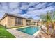 Backyard pool features a travertine deck, waterfall feature, turf grass, and view of the play area at 14413 W Dahlia Dr, Surprise, AZ 85379