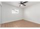 This bedroom features a ceiling fan, wood flooring, and a bright, minimalist aesthetic with a single window at 1649 W Carmel Ave, Mesa, AZ 85202