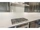 Close-up on modern gas stovetop and vent with quartz countertops, with stainless steel appliances at 18716 N 269Th Ln, Buckeye, AZ 85396