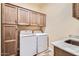 Functional laundry room with wood cabinets, counter space, and modern washer and dryer at 19535 E Via De Olivos Rd, Queen Creek, AZ 85142