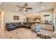 Open-concept living room with a large leather sofa, ceiling fan, and view into kitchen at 19535 E Via De Olivos Rd, Queen Creek, AZ 85142