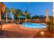Backyard pool area with patio at dusk, enhanced by ambient lighting and lush landscaping at 203 W Raven Dr, Chandler, AZ 85286