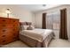 Cozy bedroom features soft neutral tones, window with blinds, bedside table lamp, and a wood dresser at 203 W Raven Dr, Chandler, AZ 85286