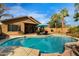 Inviting backyard with a sparkling pool, lounge chairs, an outdoor grill, and verdant palm trees at 203 W Raven Dr, Chandler, AZ 85286