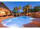 Inviting backyard pool illuminated at dusk, surrounded by palm trees, lounge chairs, and an outdoor seating area at 203 W Raven Dr, Chandler, AZ 85286