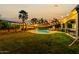A tranquil backyard with a refreshing pool, swaying palms, and ambient string lights at 21266 S 213Th Pl, Queen Creek, AZ 85142