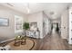 Neutral hallway with wood flooring, white trim, a decorative table, and an open view to the living room at 21266 S 213Th Pl, Queen Creek, AZ 85142