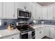 Close-up of a kitchen featuring stainless steel appliances, white cabinets, and modern backsplash at 21266 S 213Th Pl, Queen Creek, AZ 85142