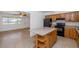 Open concept kitchen with island, wooden cabinets, and black appliances next to living room at 2262 E Javelina Ave, Mesa, AZ 85204