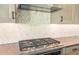 This modern kitchen features a stainless steel KitchenAid vent hood and stovetop set against a tile backsplash at 27046 W Rockwood Dr, Buckeye, AZ 85396