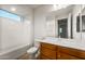 Well-lit bathroom with a combo tub and shower, wooden vanity, and a large mirror at 27110 W Adam Ave, Buckeye, AZ 85396