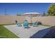 Inviting backyard featuring a seating area with bright blue chairs and an umbrella for shade at 3662 E Megan St, Gilbert, AZ 85295