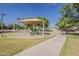 Community playground featuring a covered play structure, benches, and pathway surrounded by green grass at 3662 E Megan St, Gilbert, AZ 85295