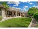 Spacious backyard featuring artificial turf, a covered patio, an outdoor kitchen, and lush landscaping for serene outdoor living at 3945 E Cherry Hills Dr, Chandler, AZ 85249
