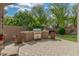 Stylish outdoor kitchen with a stainless steel grill and built-in countertops surrounded by lush greenery and potted flowers at 3945 E Cherry Hills Dr, Chandler, AZ 85249