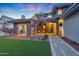 Inviting front porch features stone pillars, custom pavers, manicured lawn, and an elegant entrance with blooming trees at 4098 N Golf Dr, Buckeye, AZ 85396
