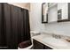 A bathroom featuring a toilet, sink, vanity, medicine cabinet, and a black shower curtain at 10723 N 80Th Ln, Peoria, AZ 85345