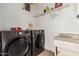 A laundry room with a washer and dryer set, a shelf, and cream walls at 10723 N 80Th Ln, Peoria, AZ 85345