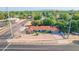 A wide aerial angle shows a cozy blue home with a red roof, surrounded by lush green trees and neighborhood streets at 140 W University Dr, Mesa, AZ 85201