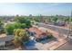 A high-angle aerial showing a charming blue home with a red roof, surrounded by lush greenery and quiet streets at 140 W University Dr, Mesa, AZ 85201
