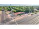 A wide aerial shot shows a blue home with a red roof, surrounded by greenery and neighborhood streets at 140 W University Dr, Mesa, AZ 85201