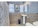 Comfortable bathroom featuring tiled walls, pedestal sink, updated fixtures, and decorative art at 140 W University Dr, Mesa, AZ 85201