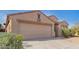 Tan single-story home with a two-car garage, desert landscaping and some greenery under a blue sky at 1541 W Lynne Ln, Phoenix, AZ 85041