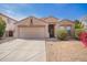 Tan single-story home with a two-car garage, desert landscaping and some greenery under a blue sky at 1541 W Lynne Ln, Phoenix, AZ 85041