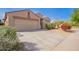 Tan single-story home with a two-car garage, desert landscaping and some greenery under a blue sky at 1541 W Lynne Ln, Phoenix, AZ 85041