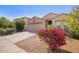 Tan single-story home with a two-car garage and desert landscaping, with bougainvillea under a blue sky at 1541 W Lynne Ln, Phoenix, AZ 85041