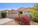 Tan single-story home with a two-car garage and desert landscaping, with bougainvillea under a blue sky at 1541 W Lynne Ln, Phoenix, AZ 85041