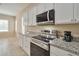Updated kitchen with stainless steel appliances, granite countertops, white cabinets, and natural light at 16955 W Cypress St, Goodyear, AZ 85395
